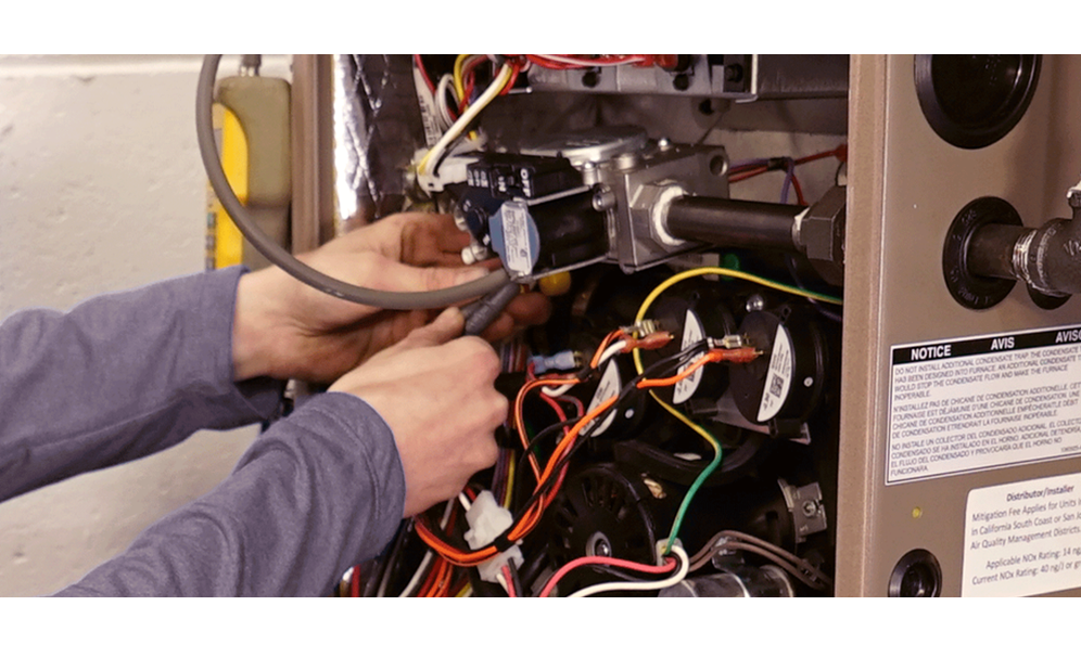 A person's hands fixing an open HVAC equipment
