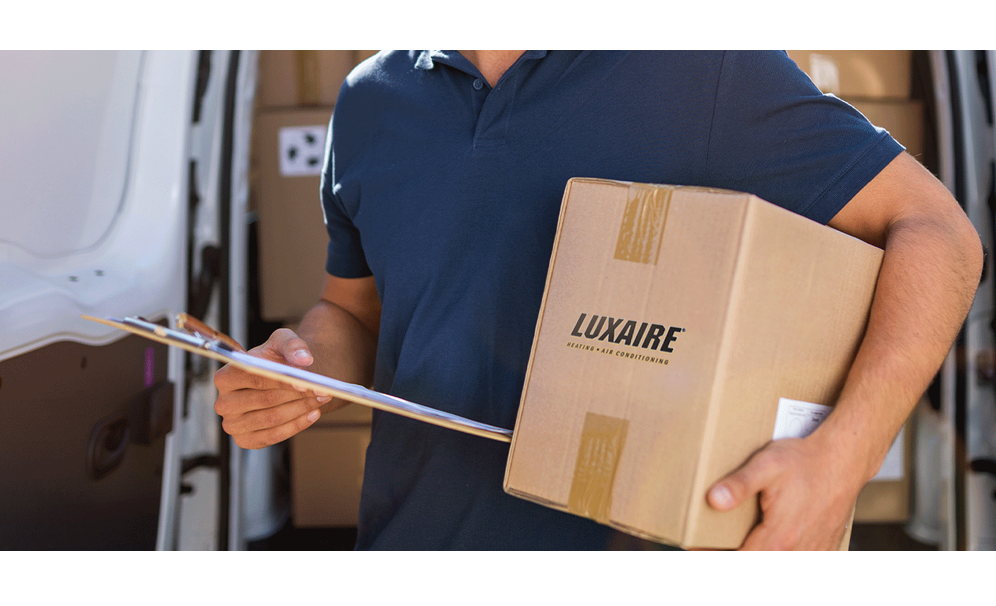 A mailman holding a cardboard box under his arm and holding a clipboard in his other hand